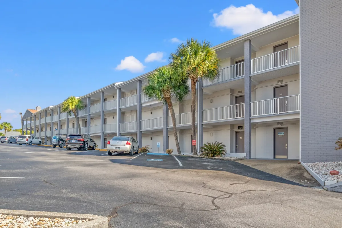 Overlooking the property, this photo shows several balconies nestled among palm trees, with a casual glimpse of cars parked below. The composition highlights the balconies as personal outdoor spaces and subtly references the Golden Mile setting, reinforcing the connection between private and community areas.