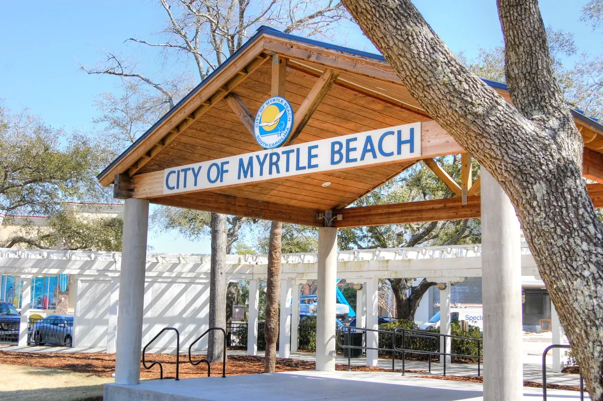 This image shows the City of Myrtle Beach pavilion with its welcoming sign and a backdrop of lush trees, suggesting a hub of local events and community engagement. The setting conveys a sense of place and serves as a gateway to the city's many attractions.