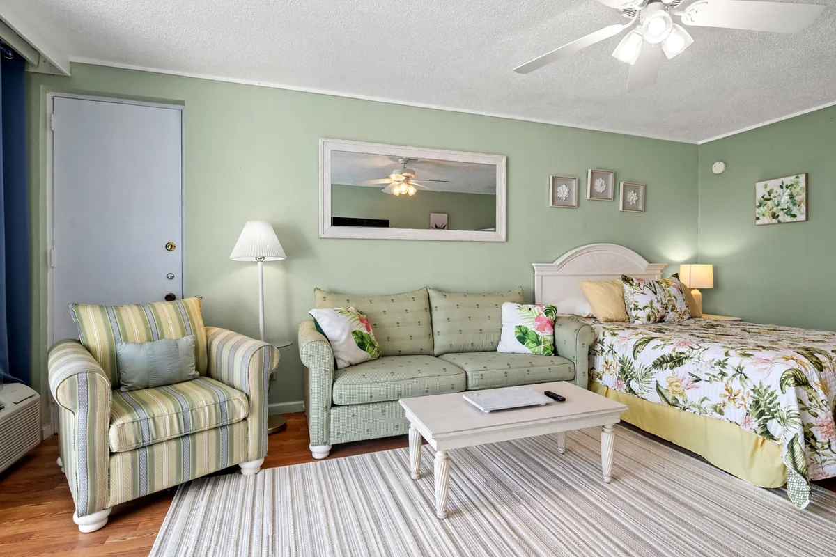 This scene presents a cozy corner of the sleeping area, focusing on a comfortable sofa, bed, and a coffee table with a lamp. The warm lighting and tasteful wall décor create a sense of coziness and relaxation, ideal for winding down after a busy day. The setup feels inviting and supports multiple uses, from reading and relaxing to socializing.